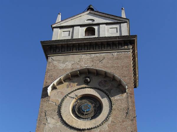 Brick clock tower with astronomical dial in Mantua, clear blue sky