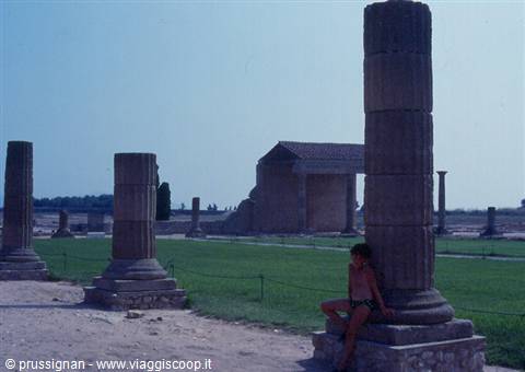 Boy sitting beside an ancient column among archaeological ruins