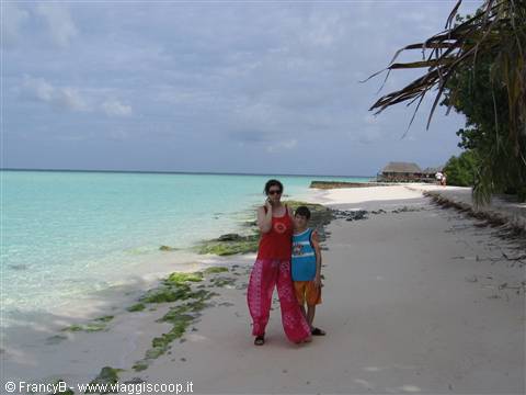 Mother and child in colorful clothes on white sand by the turquoise sea