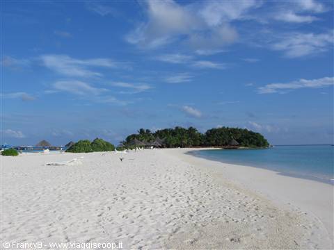White sand beach with loungers, green islet and turquoise tropical waters