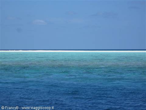 Turquoise and emerald lagoon waters with coral reef on the horizon