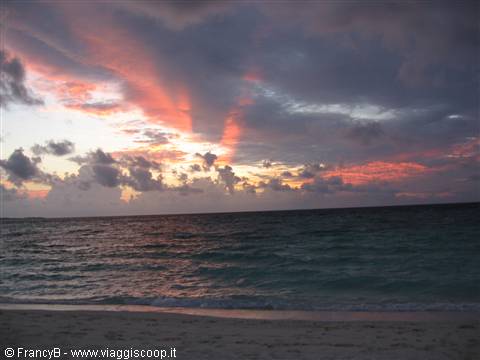 Red and grey clouds over wavy sea and sandy beach