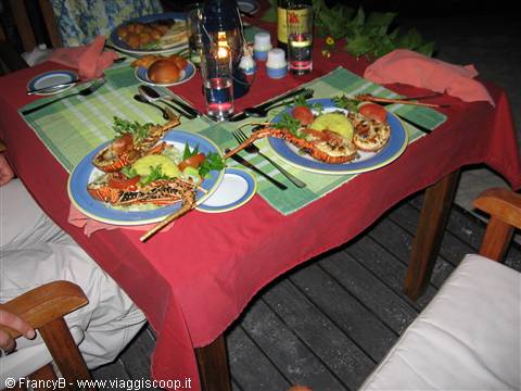 Lobster dinner on a wooden terrace, red tablecloth and lit candle