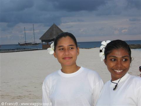 Two smiling girls with white flowers in their hair on the beach