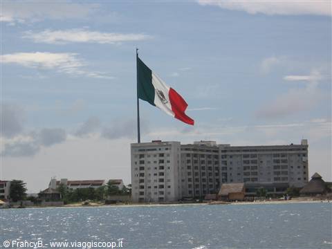 Large Mexican flag waving above a seaside hotel in Cancún