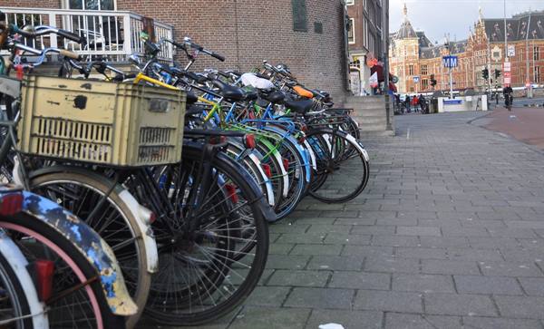 Bicycles lined up against a brick wall, Amsterdam station visible in the background