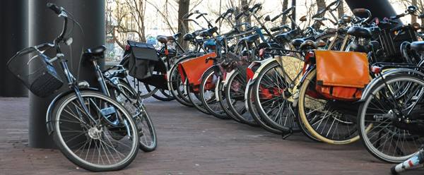 Bicycles lined up beside a pylon, orange and black bags, winter light