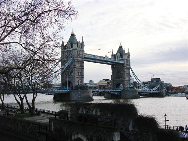 London's Tower Bridge over the Thames, cloudy sky, bare branches in the foreground