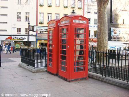 Two red cast-iron telephone boxes on stone pavement in London