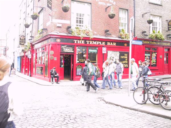 Crowd outside the red Temple Bar pub on cobbled Dublin street