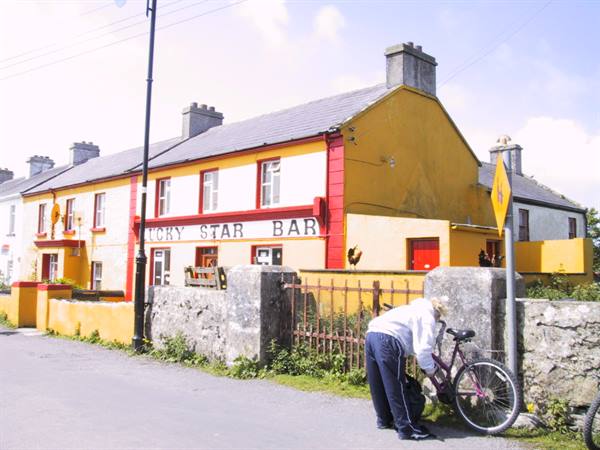 Cyclist in white jacket beside bicycle outside the yellow Petty Star Bar