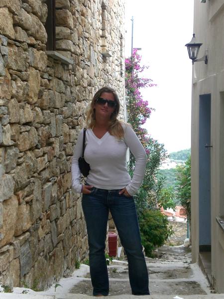 Woman in white sweater and sunglasses on stone steps between stone walls and bougainvillea