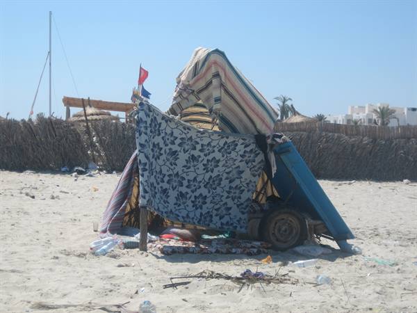 Shelter of fabrics and scrap on a sandy beach with palm trees