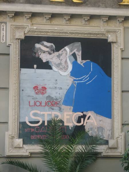 Painted Strega liqueur sign of woman in blue dress, stone frame