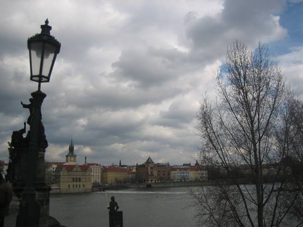 Cast-iron lamp on Charles Bridge, Vltava river and historic Prague houses