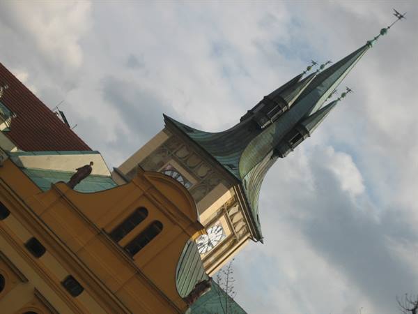 Clock tower with green copper spire rising against cloudy sky