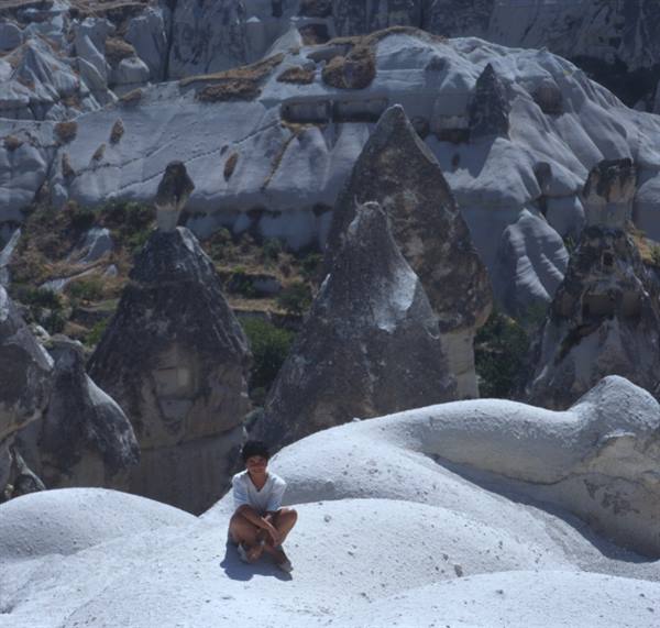 Boy sitting on white rock among Cappadocia fairy chimneys