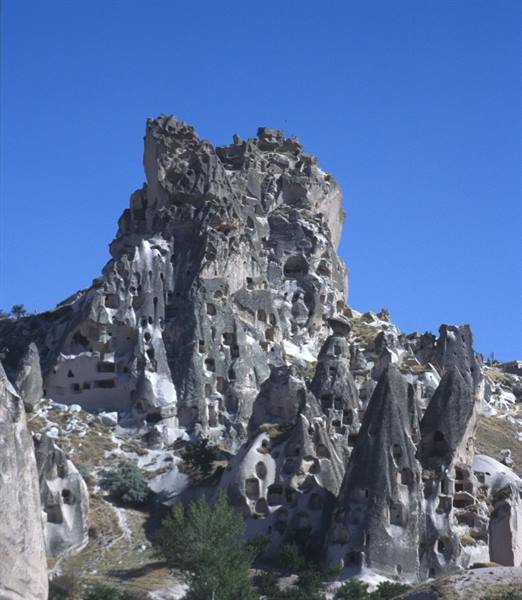 Hewn tuff rock formations in Uchisar, Cappadocia, under clear blue sky