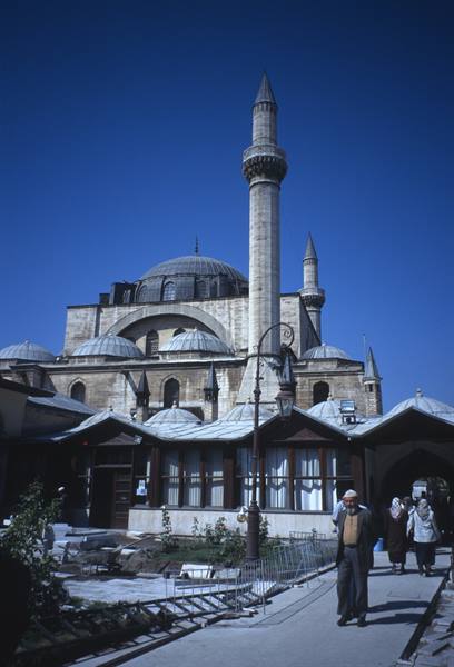 Men walk past the stone mosque with its tall minaret in Konya