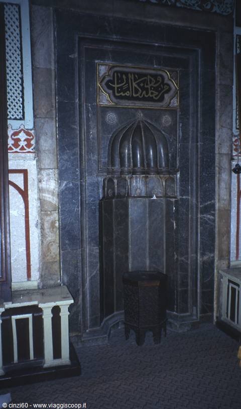 Dark marble mihrab with golden calligraphy inside a mosque
