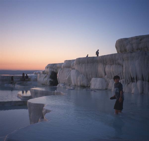 Boy wading in white travertine pools at Pamukkale