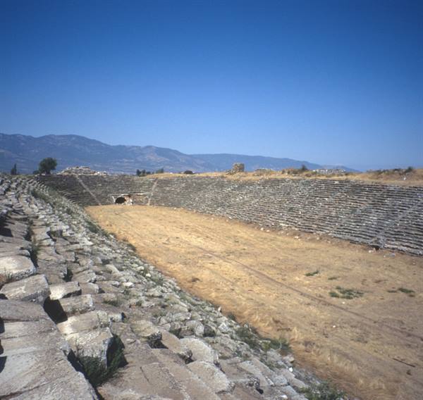 Ancient stadium of Aphrodisias, stone seating rows under blue sky
