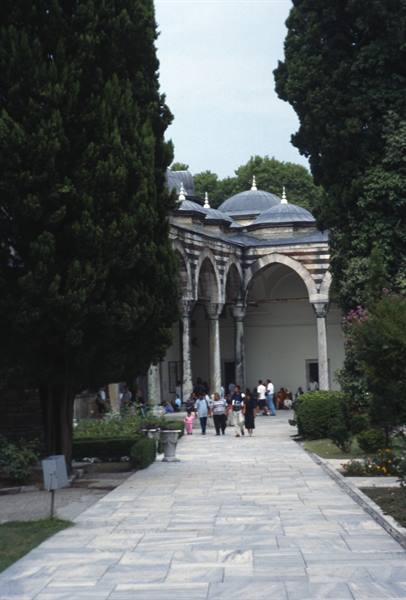Visitors walk through Topkapi's stone-paved courtyard beneath arcades and lead domes