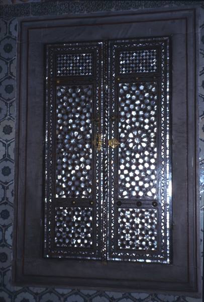 Wooden door inlaid with mother-of-pearl, marble frame, blue floral tiles alongside