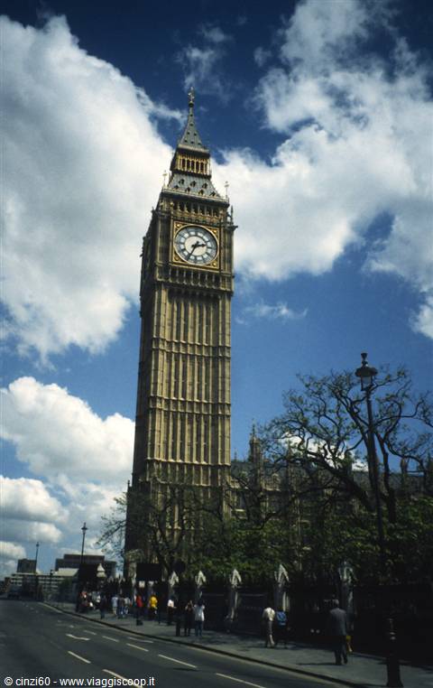Big Ben in London rises against a blue cloudy sky, pedestrians walking below