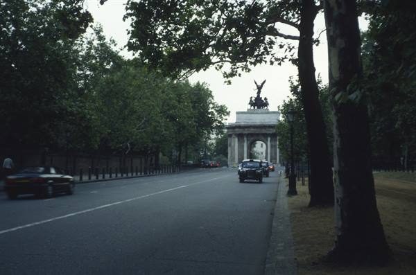 Wellington Arch at Hyde Park Corner, cars on tree-lined road under grey light