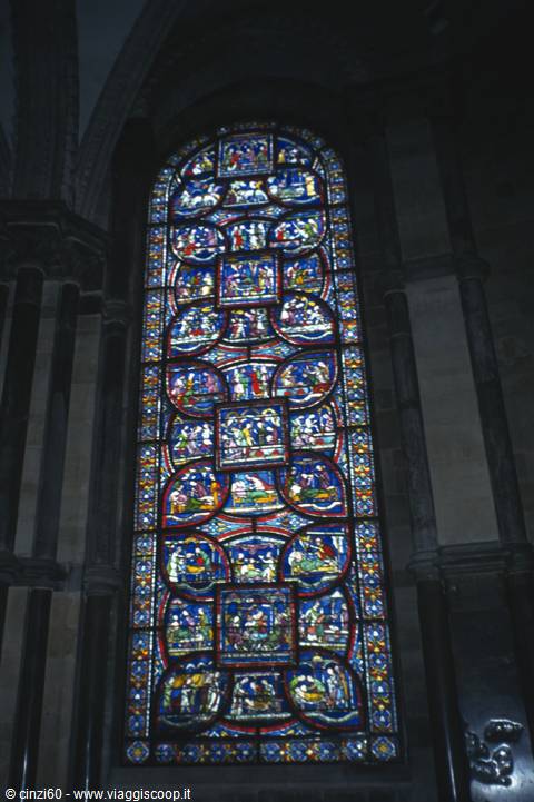 Medieval stained glass window with blue and red panels inside Chartres Cathedral