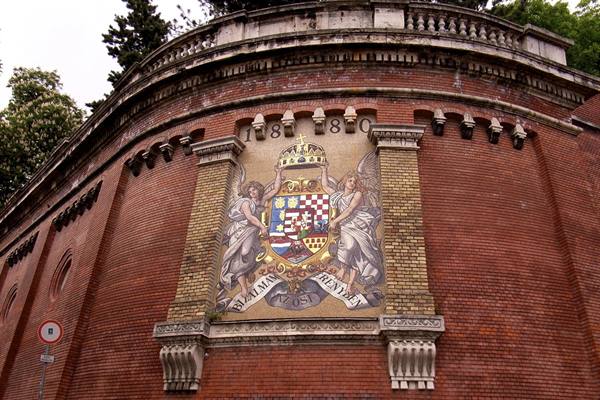 Coat of arms mosaic with crown and angels on 1880 brick wall, Zante