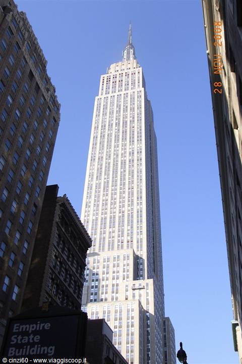 Empire State Building towering among Manhattan skyscrapers, sunlight, clear blue sky