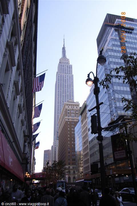 American flags and crowd along the street with the Empire State Building rising above skyscrapers