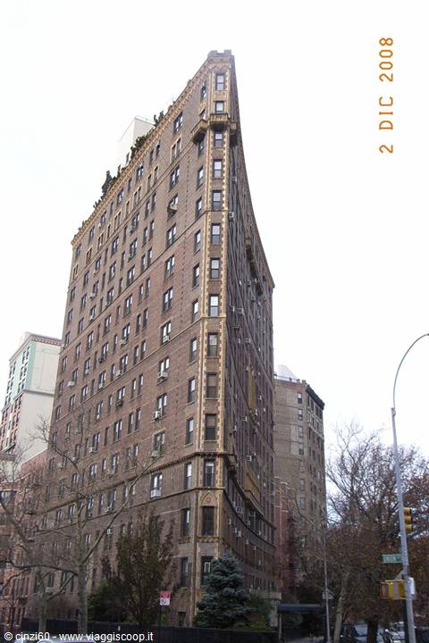 Curved corner brick apartment building, overcast sky, bare trees and traffic light