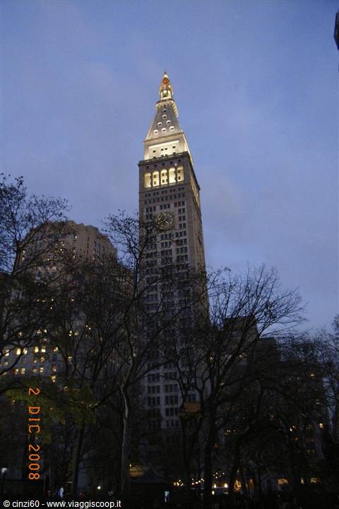 The illuminated Metropolitan Life tower at dusk among bare branches, New York