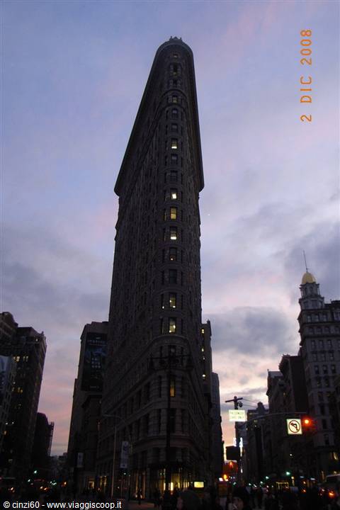 Flatiron Building in New York, lit windows against a cloudy sky