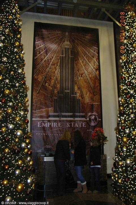 Visitors by the Empire State Building poster between lit Christmas trees
