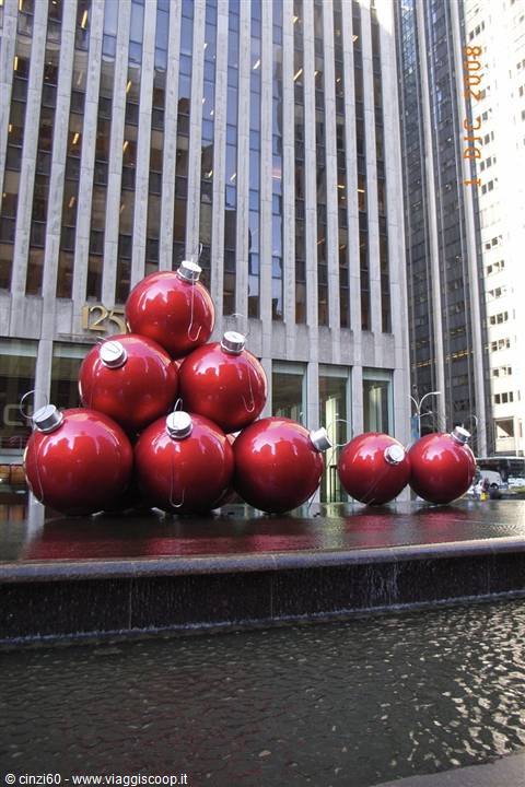 Giant red Christmas ornaments stacked on a fountain among Manhattan skyscrapers