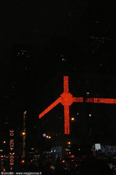 Giant illuminated red bow on building facade at night, traffic below