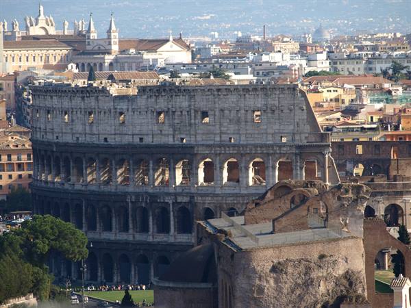 Rome's Colosseum in ancient brick and stone, daylight, tourists queueing below