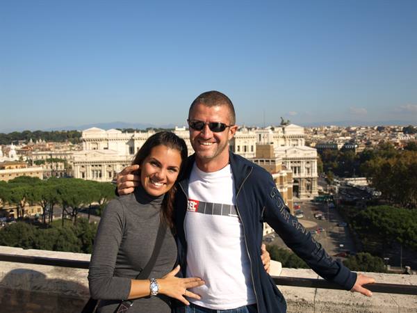 Smiling couple on a terrace in Rome, Vittoriano monument behind them