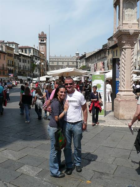 Couple embracing in Piazza delle Erbe, Verona, among market stalls and historic buildings