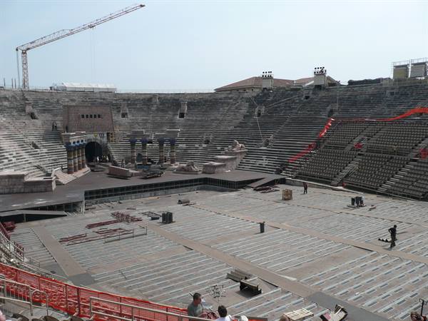 Verona Arena, stone seating tiers and stage being set up, worker at work