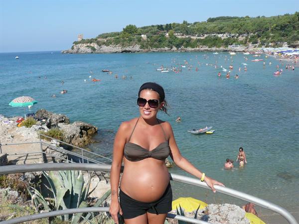 Pregnant woman in bikini by a crowded bay of swimmers and canoes