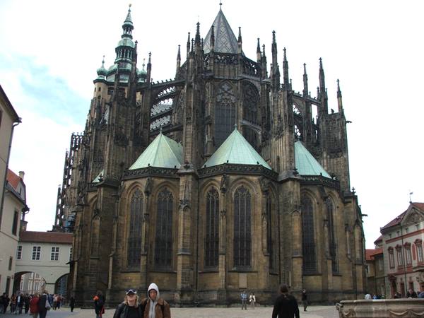 Tourists in the square before St. Vitus Cathedral in Prague, gothic spires, green roofs