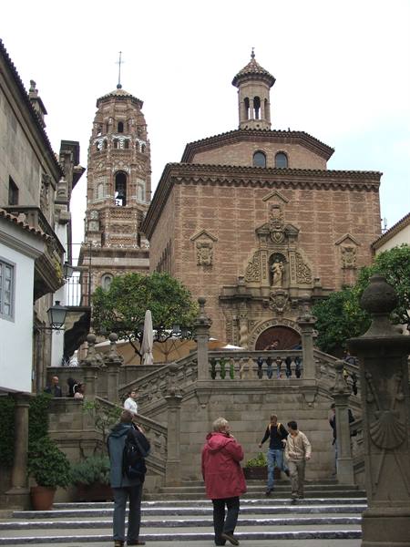 Tourists climb the stone steps in front of the brick church with bell tower