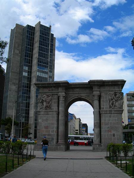 Arco de la Victoria in Madrid, carved stone arch with passerby and skyscraper behind