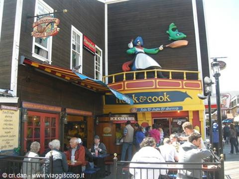 Painted wooden facade with cook sign, people at outdoor tables