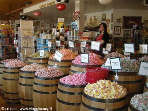 Saleswoman among wooden barrels full of colorful candy at Candy Baron
